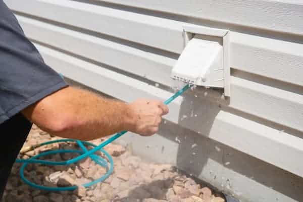 Appliance repair Vancouver technician cleaning a dryer vent and removing lint buildup for proper airflow and safety